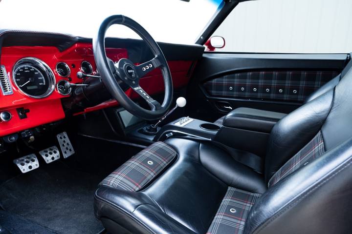 Black leather seats with plaid inserts and a Sparco wheel in the 1969 Camaro
